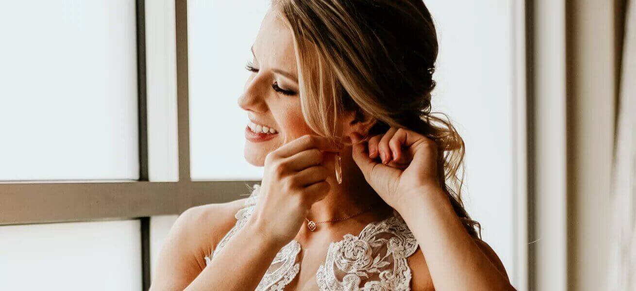 Photo of bride puting on Bestow Bridal earrings